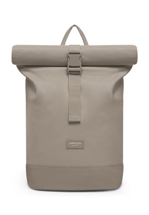 Beige rugzak met oprolbare bovenkant, een gesp aan de voorkant en een bovenste draaggreep, met een klein rechthoekig etiket met de tekst "Larkson Hamburg".