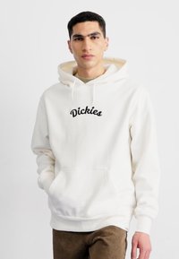 Sudadera blanca con cordón, con un logo negro bordado "Dickies" en el pecho. Tejido suave, bolsillo frontal tipo canguro y puños acanalados.