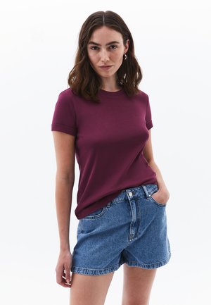Kastanjebrun crew-neck T-shirt med opsmøgede korte ærmer, parret med højtaljede denimshorts. Blød tekstur og afslappet pasform.