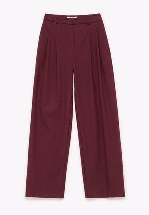 Pantaloni larghi bordeaux con una texture liscia, frontale plissettato e vita a media altezza. Progettati con cuciture sottili e passanti per cintura.