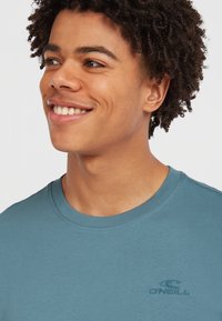 Lyseblå bomulds T-shirt med rund hals, der har et lille tonalt logo på brystet, glat tekstur og korte ærmer.
