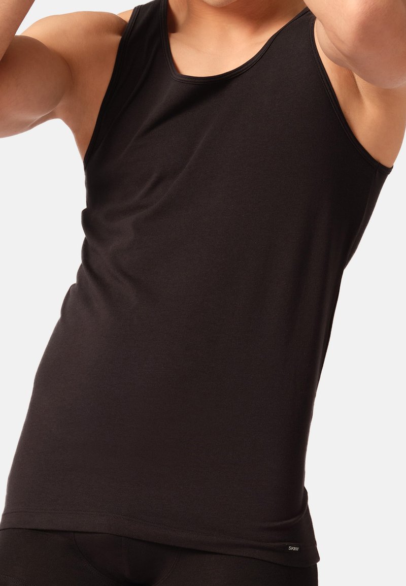 Sort tanktop lavet af glat, strækbart stof; ærmeløs design med en rund halsudskæring og en tætsiddende pasform. Diskret logo-detalje ved kanten.