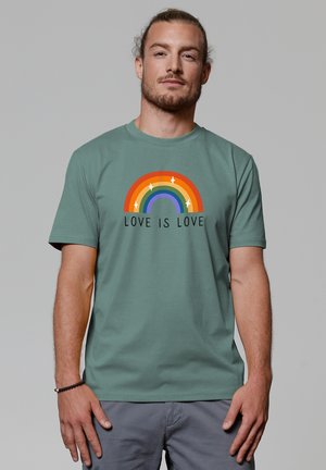 Green cotton t-shirt with short sleeves, featuring a multicolored rainbow design and the text "LOVE IS LOVE" in black below.