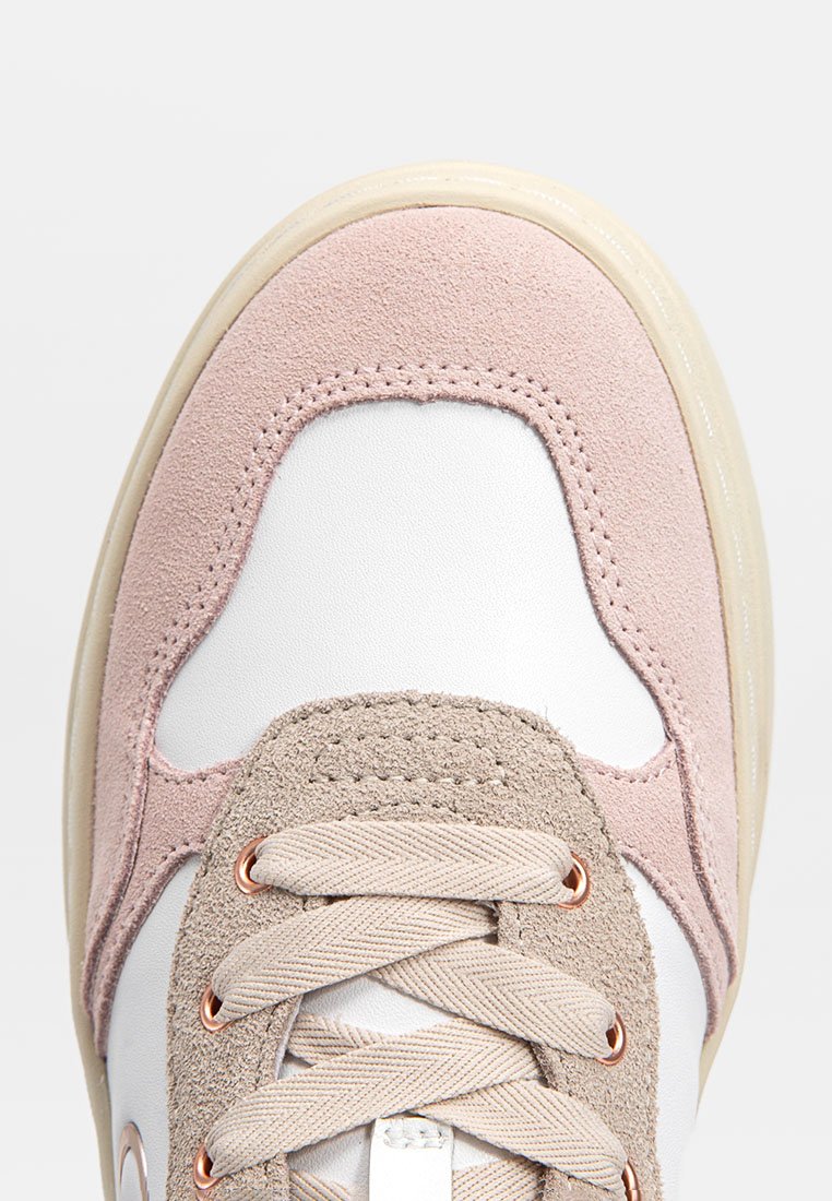 Sneaker con una base in pelle bianca e accenti in suede rosa. Presenta un pannello di lacci beige, occhielli in rame e suola testurizzata per aderenza.