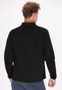 Sort langærmet pullover lavet af et glat, strækbart stof med en opretstående krave og uden synlige lukninger, vist fra ryggen.
