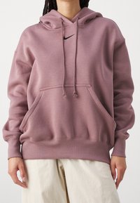 Sudadera con capucha en color rosa apagado, hecha de material suave. Presenta un bolsillo frontal, cordones y un pequeño logo negro en el pecho.