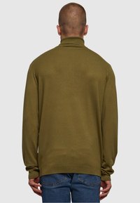 Olivgrön polotröja med ribbad krage och ärmslut. Lätt stickad tyg; bakvy som visar en enkel, ren design och passform.