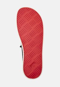 Suola della scarpa realizzata in materiale gommoso rosso con un motivo testurizzato. I bordi sono bianchi, con marchi del brand vicino al tallone e la taglia indicata.