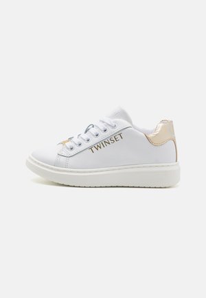 Sneaker bianco con tomaia in pelle liscia, logo dorato "TWINSET" sul lato e un accento dorato a contrasto sul tallone. Suola leggera.