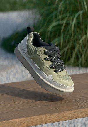 Green and gray sneaker with a textured upper, black laces, and a thick, light gray sole, displayed against a natural background.