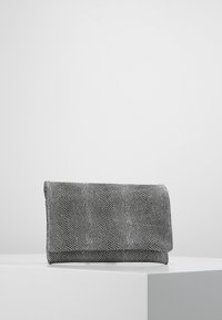 Czarnobiała teksturowana kopertówka z klapką na zakładkę, z powierzchnią o wzorze przypominającym tkaninę. Kompaktowy, prostokątny kształt.