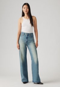 Lichtblauwe hoge taille wijde jeans gemaakt van denim, met vervaagde gebieden bij de dijen en een klassieke vijf-pocket design.