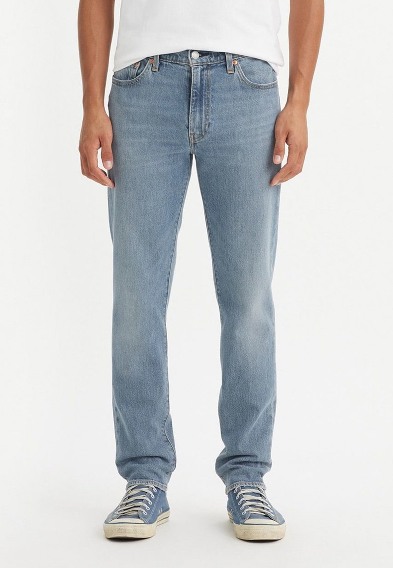 Lyseblå denimjeans med rett snitt, med fem lommer, knappestolpe og subtil bleking for et slitt utseende.