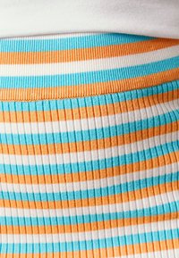 Tessuto texturizzato che mostra strisce orizzontali in turchese, arancione e bianco. Il design presenta una texture a coste e un netto contrasto di colori.