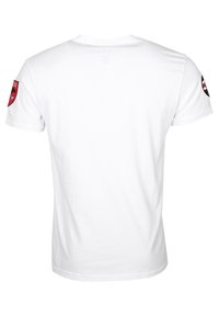 Witte T-shirt met korte mouwen, voorzien van een ronde hals en twee rode en zwarte patches met een logo op elke mouw. Gladde katoenen stof.