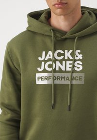 Olivegrüner Hoodie mit einem Frontlogo-Druck in Weiß. Er verfügt über eine Kordelzugkapuze, gerippte Ärmelbündchen und eine glatte Baumwollstofftextur.