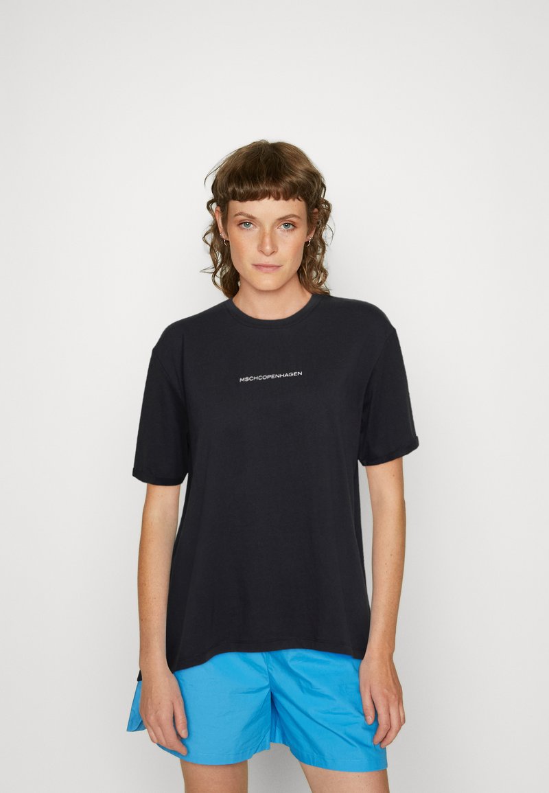 Black cotton t-shirt with short sleeves, featuring "MSCHCOPENHAGEN" printed in white on the chest. Model wears blue shorts.