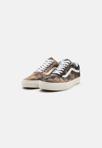 Kamuflasje lerret sneakers med hvite snører og gummisåle. Har mørke og lyse brune mønstre, kontrasterende hvit side stripe, og myk tekstur.