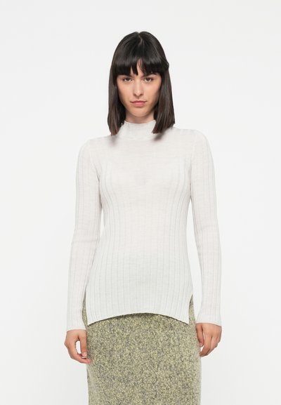 Maglietta a maniche lunghe grigio chiaro a coste con collo alto, caratterizzata da un design aderente e fessure ai lati dell'orlo, indossata con una gonna verde texturizzata.