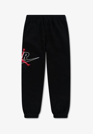 Pantalon de survêtement noir avec taille et chevilles élastiques, muni d'un logo Air Jordan Jumpman rouge et blanc sur la cuisse gauche.