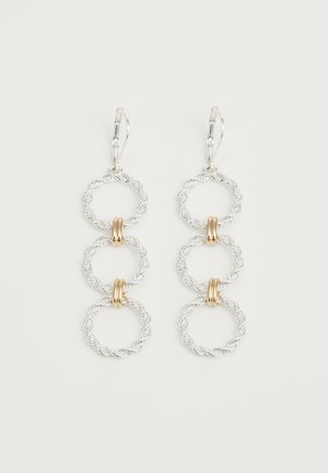 Boucles d'oreilles en métal argenté comprenant trois anneaux entrelacés, accentués de deux anneaux en métal doré. La texture est à la fois tordue et lisse.