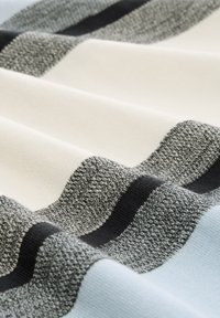 Strickstoff mit abwechselnden horizontalen Streifen in Grau, Schwarz, Creme und Hellblau, die verschiedene Texturen und Muster aufweisen.