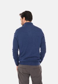 Maglione a collo alto di colore blu navy, con polsini e orlo a coste. Realizzato in un morbido tessuto testurizzato. Presenta una silhouette aderente.