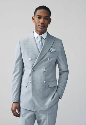 Light blue plaid double-breasted suit with notched lapels, two front pockets, and white buttons. Accompanied by a light blue tie and pocket square.