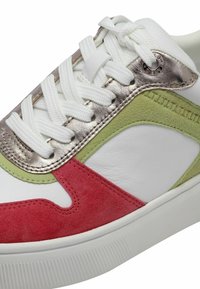 Multicolored sneaker featuring white leather, red and green suede accents, metallic silver detailing, and textured rubber sole.