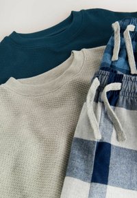 Dva teksturirana hoodieja v temno teal in svetlo sivi barvi, složena nad sivimi in modrimi karirastimi hlačami s vrvico.