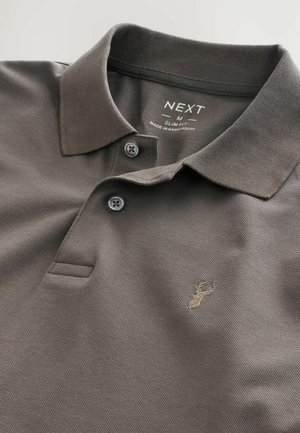 Polo din material slim fit, de culoare gri închis, cu un textură specială, două nasturi la guler și un detaliu brodat discret cu un cerb auriu.