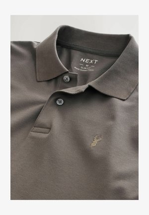 Polo din material slim fit, de culoare gri închis, cu un textură specială, două nasturi la guler și un detaliu brodat discret cu un cerb auriu.