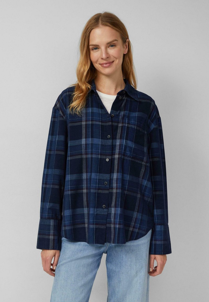 Marineblauwe geblokte shirt met knopen aan de voorkant, lange mouwen en een ontspannen pasvorm. Kenmerkt zich door witte en lichtblauwe accenten in het patroon.