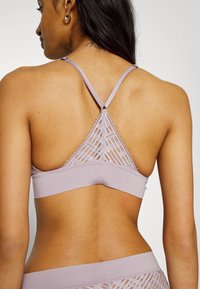 Lila bralette s čipkastim dizajnom i geometrijskim uzorcima, s podesivim trakama i glatkim pojasom za dodatnu udobnost.