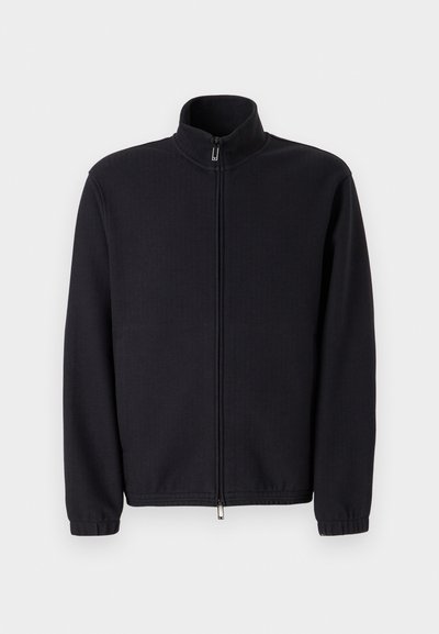 Čierna zipsová bunda vyrobená z textúrovaného materiálu, s vysokým golierom a elastickými manžetami, so strihaním do rovna a bez viditeľných ozdôb.