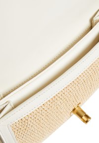 Bolso tejido en color beige y blanco con un ribete de cuero suave. Presenta un cierre de metal de tono dorado y un diseño estructurado.