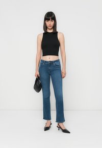 Svart ermeløs crop topp, blå denim flare jeans, svarte spisse hæler og en liten svart veske. Glatt stoff, klassisk passform og uformell stil.