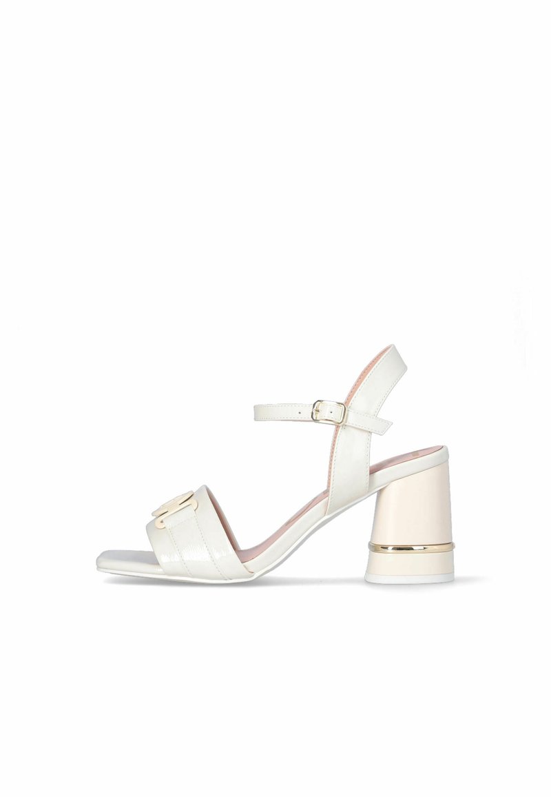 White open-toe sandal with a block heel, ankle strap with buckle, and decorative buckle on the front strap, displayed on a white background.