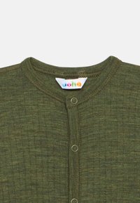 Grønn ribbestrikket cardigan med rund hals, trykknapper foran og en fargerik merkelapp på kragen.