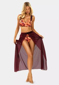Dwuczęściowy bikini w kwiatowy wzór w odcieniach pomarańczowym i czerwonym, zestawiony z marszczoną spódnicą w kolorze bordowym, z przezroczystego materiału, z teksturowanym wzornictwem i rozcięciem.