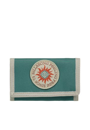 Portefeuille en toile verte avec un écusson rond orné d'un motif de soleil en rouge et orange, bordé de tissu beige. Forme pliée et compacte.