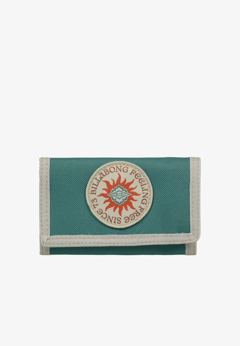 Portefeuille en toile verte avec un écusson rond orné d'un motif de soleil en rouge et orange, bordé de tissu beige. Forme pliée et compacte.