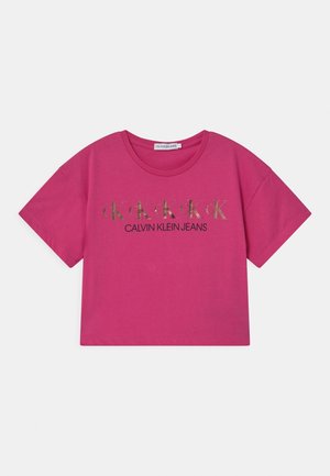 Fuchsia kortærmet t-shirt med rund halsudskæring, trykt med gentagne gyldne "ck" logoer og "CALVIN KLEIN JEANS" tekst i sort.