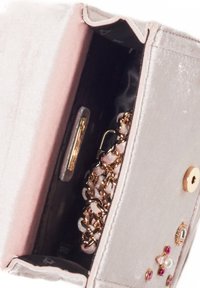 Grå sammetskuvert med en rosa inredning, gulddetaljer, kedjedetalj och dekorativa stenar på utsidan. Öppen klaff med en mjuk textur.