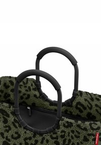 Bolso de estampado de leopardo verde con asas de goma negra y cremallera. El material parece texturizado y similar a polar, con notables acentos en las asas.
