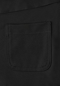 Close-up of a black fabric pocket with visible stitching on a garment.