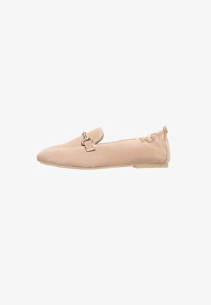 Beige suede slip-on shoes with a flat sole, pointed toe, decorative strap with a metallic accent, and stitched detailing along the edges.