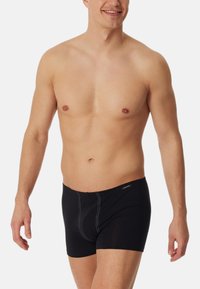 Caleçons boxers noirs avec une coupe ajustée, fabriqués à partir d'un matériau doux. Présentent des coutures contrastées et une ceinture de marque.