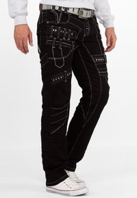 Pantaloni cargo neri con cuciture bianche, dotati di molteplici tasche e design slim fit, completati con una cintura grigia a trama.