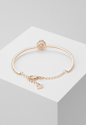 Rose gold bracelet featuring a textured band, decorative clasp with a flower design, and a small swan charm with sparkling accents.
